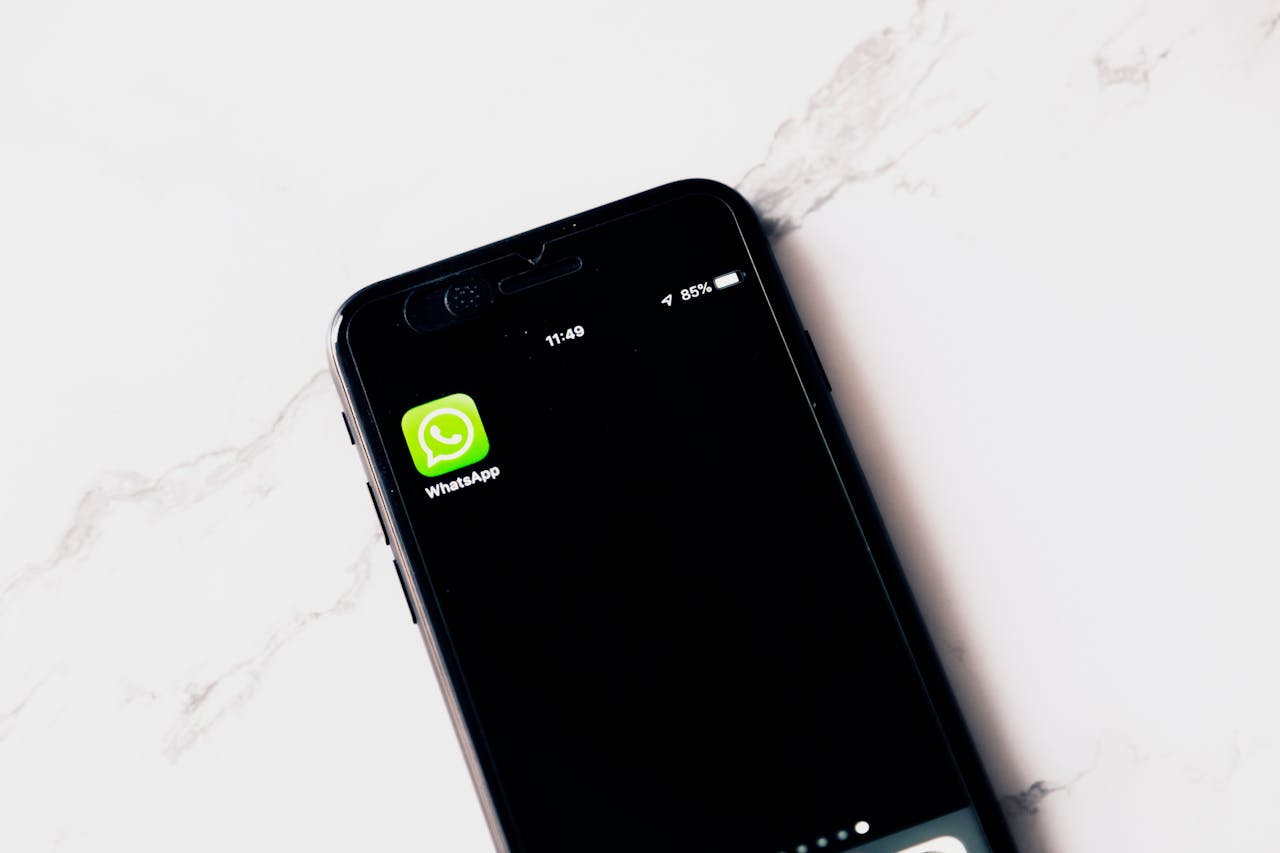 Close-up image of a smartphone displaying WhatsApp on a white table.